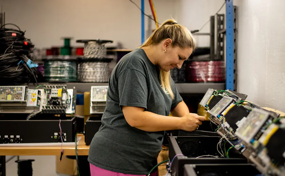 A CI8 Group operator working with an electrical assembly at a production station.