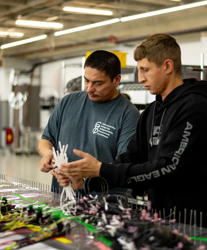 Two team members reviewing electrical assembly work at a CI8 Group production bench.