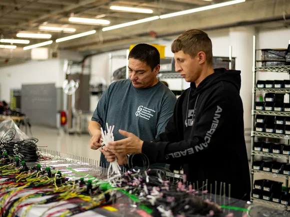 Two team members reviewing electrical assembly work at a CI8 Group production bench.