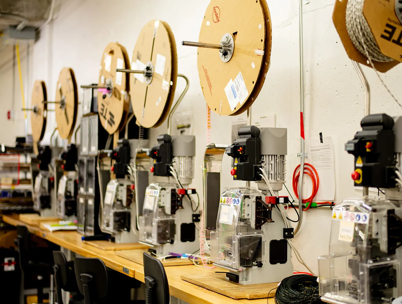 Wire reels and assembly equipment arranged along a production bench at CI8 Group.