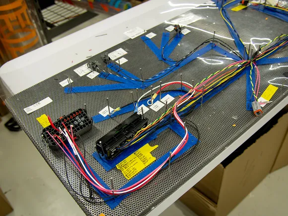 A custom wire harness laid out on an assembly board with connectors and routed branches.
